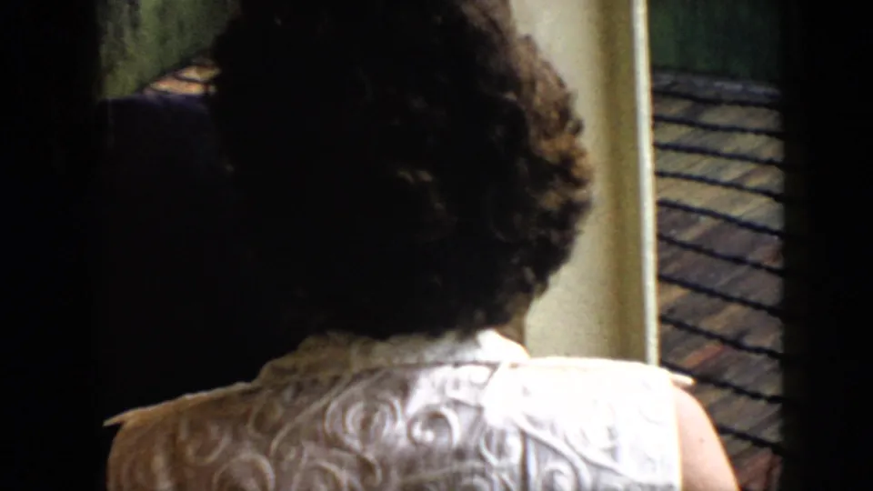 1956 Cuba home-movie frame showing a woman in a light patterned dress from behind near a dock or balcony edge.