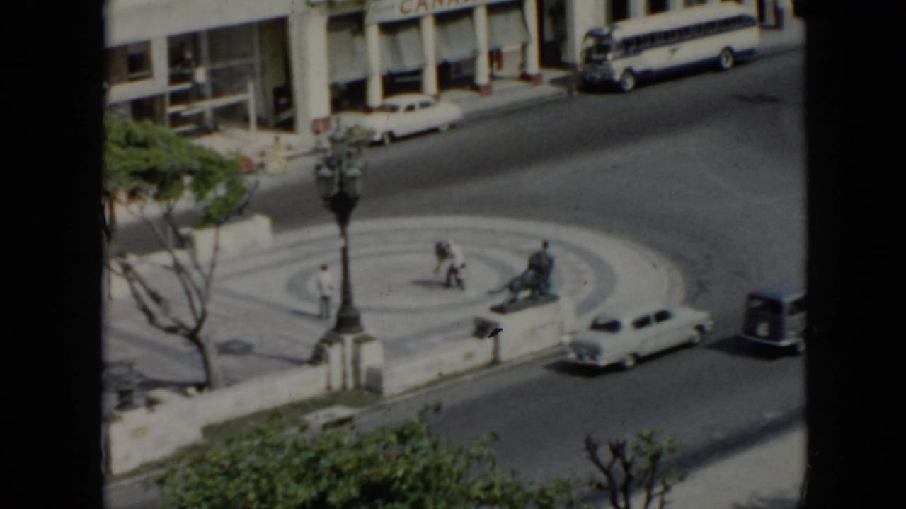 Elevated view of a circular city turnaround with cars, pedestrians, lamppost and storefronts.