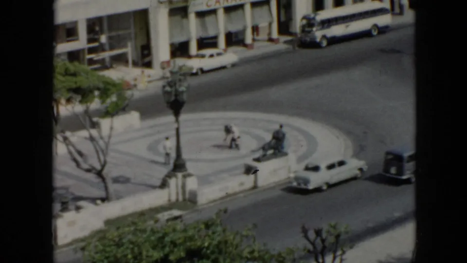 1956 Cuba footage shows an elevated street view with classic cars, pedestrians, a circular turnaround and a Canada Dry storefront sign.