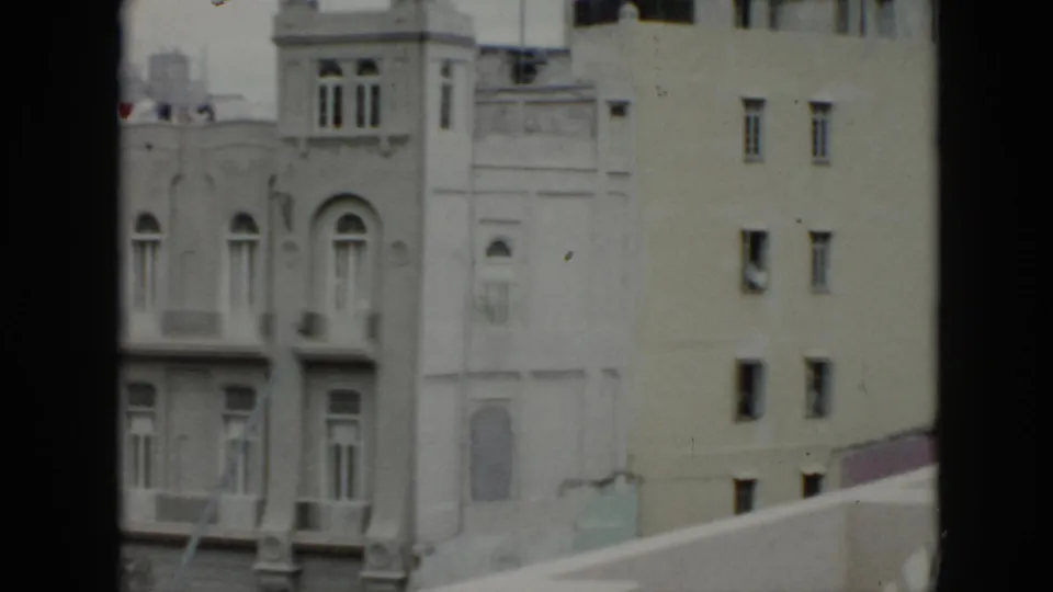1956 Cuba balcony-view frame with ornate windows on one facade and a plainer neighboring wall with small rectangular windows.