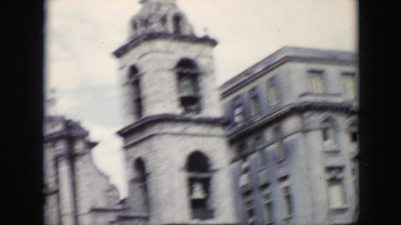 Soft view of a bell tower and adjacent multi-story building from a moving vehicle.