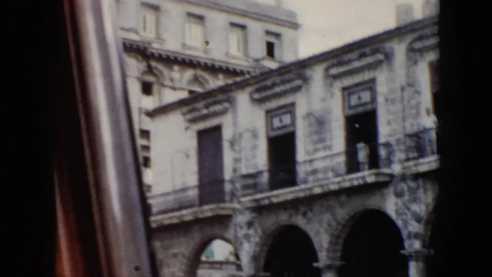1956 Cuba city view of an ornate masonry facade with balconies, arched openings, and a possible person in a doorway.