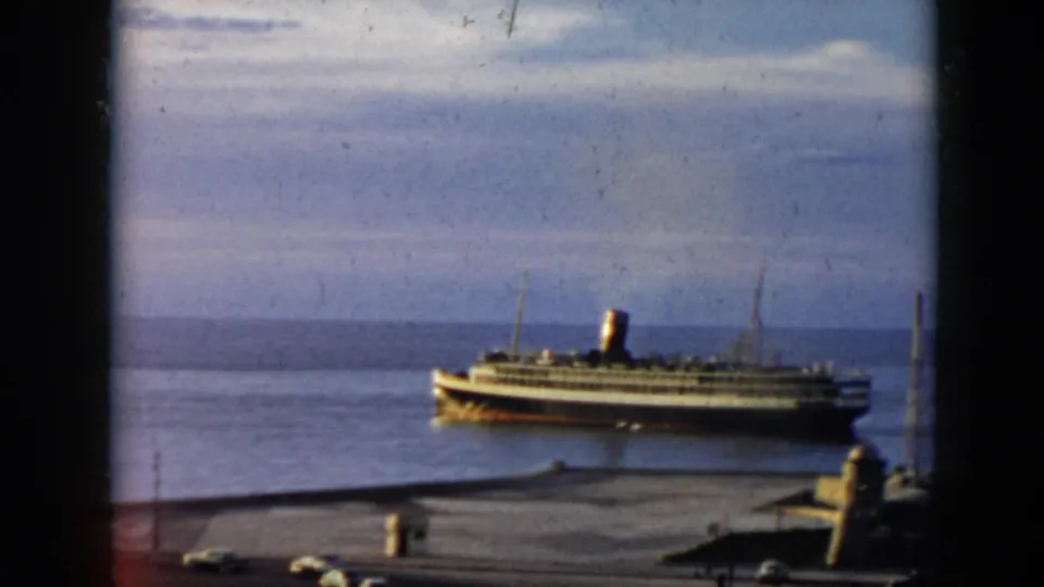 1956 Cuba port scene showing a white ocean liner with a dark smokestack docked against a cloudy sea horizon.
