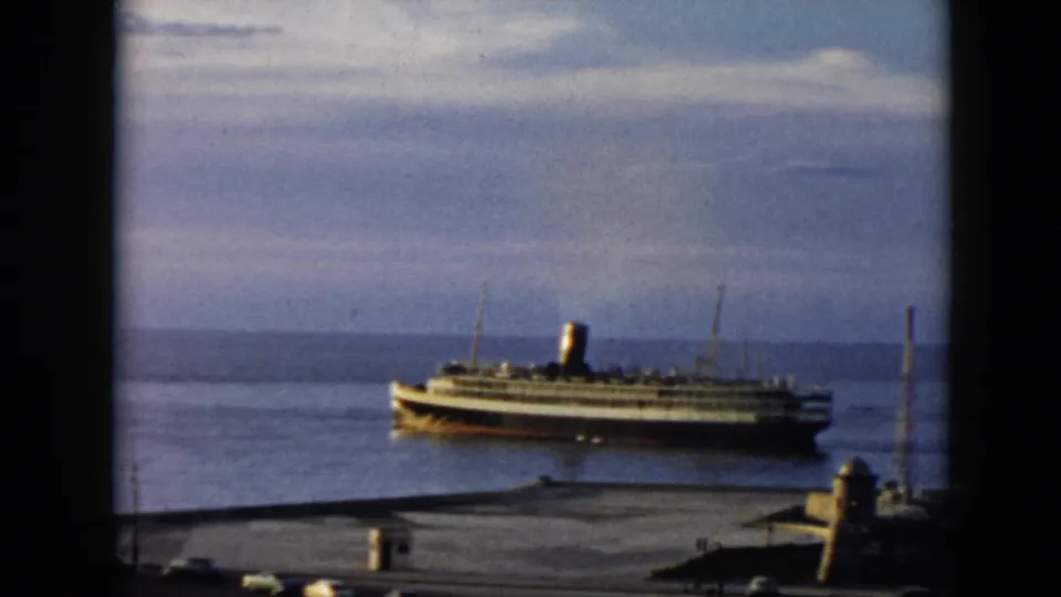 1956 Cuba home-movie frame of a docked ocean liner seen from the waterfront, with soft 8mm color and visible frame borders.