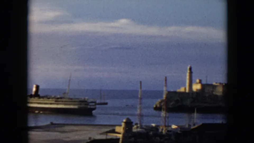 1956 Cuba harbor view with the steamship partly leaving frame and a fort-like coastal structure visible at right.