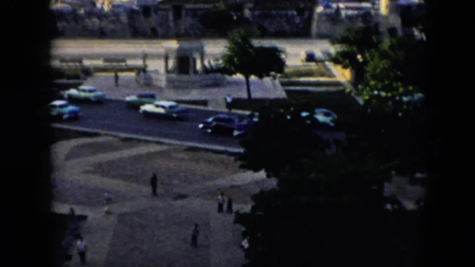 1956 Cuba home-movie frame looking down on waterfront traffic and pedestrians near Havana harbor.