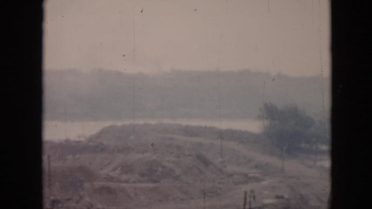 1956 Cuba coastal view showing a low hill or knoll near water, seen through a window frame in soft focus.