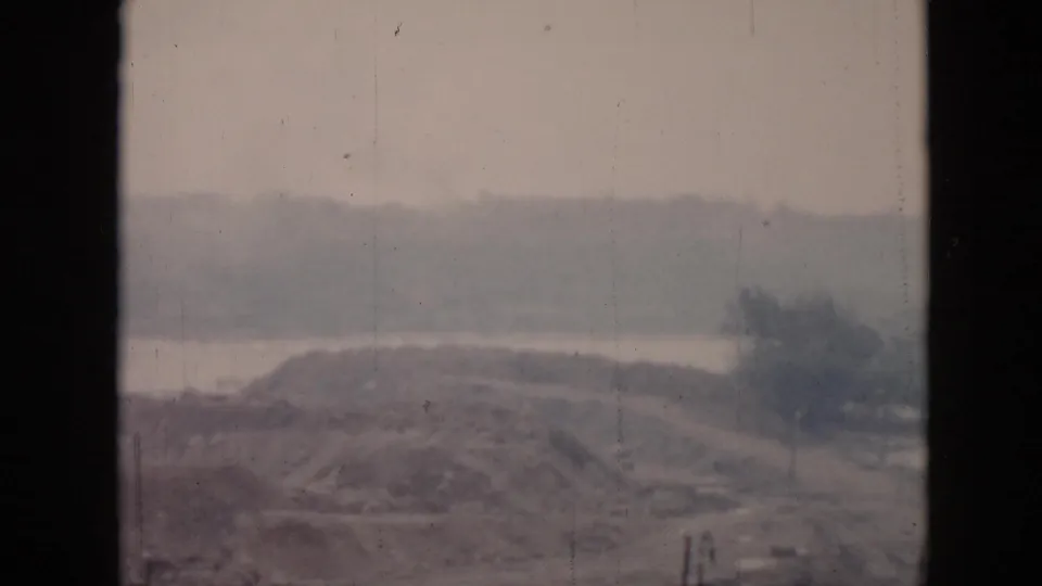 1956 Cuba coastal view showing a low hill or knoll near water, seen through a window frame in soft focus.