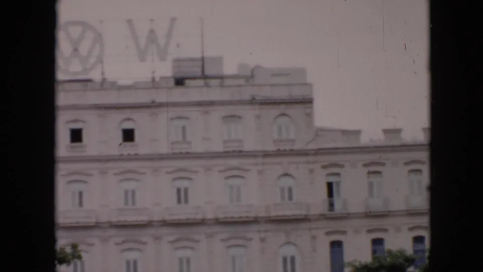 1956 Cuba frame showing the building's upper stories with a rooftop Volkswagen emblem and large letters partly visible above the facade.