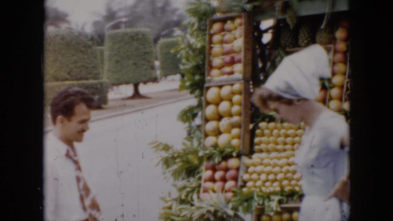 Man in a tie faces a woman near a tall fruit stand display.