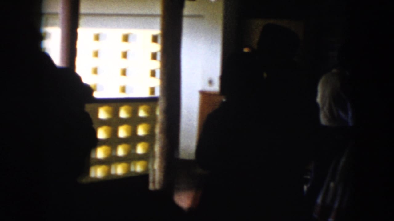 Several dark figures appear in profile near a bright wall and doorway.