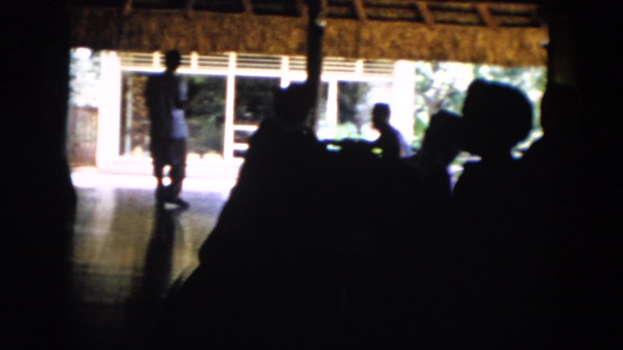 In Cuba in 1956, silhouetted figures gather inside a thatched open-air structure with sunlit exterior views behind them.