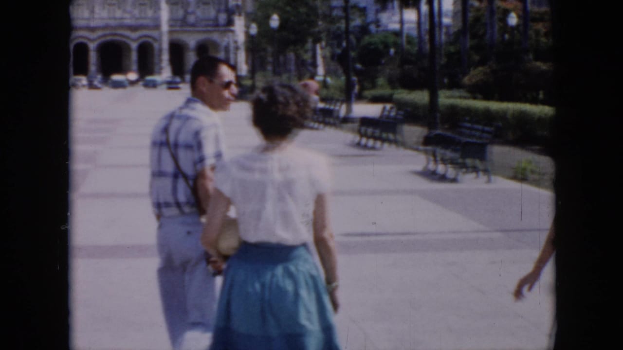 A man and woman walk ahead on a bright park walkway.