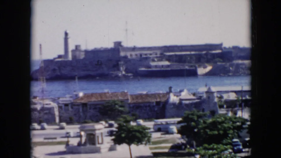 1956 Cuba home-movie view of a large harbor fortress, likely El Morro per clip metadata, seen across water from an elevated waterfront vantage.