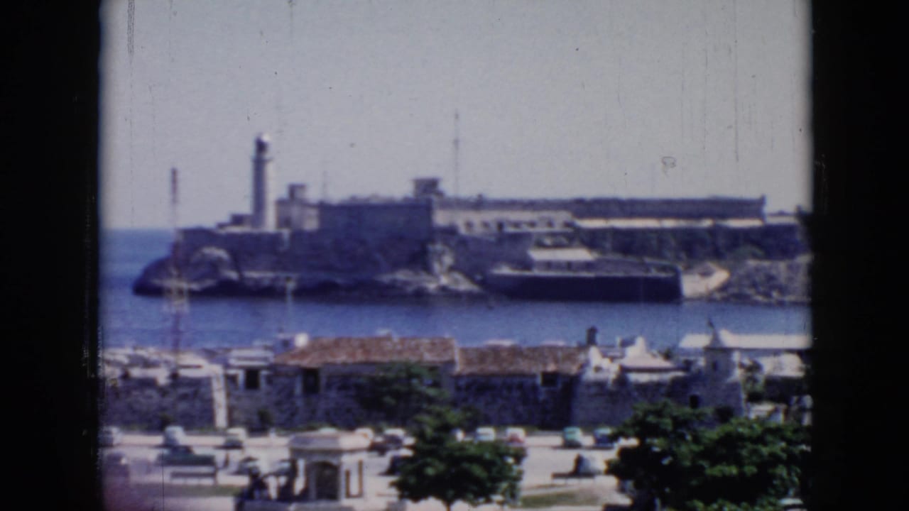 1950s Cuba home-movie view across water toward a fort-like structure with a tall tower, seen above low city buildings.