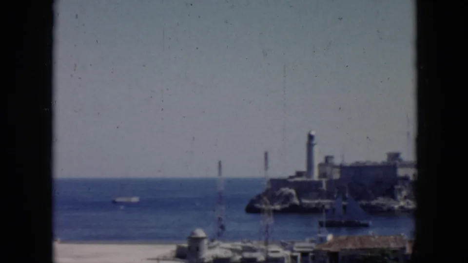 Havana harbor scene showing Morro Castle and lighthouse across the water in soft 8mm focus.