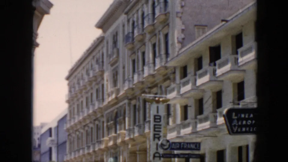 1956 Cuba street view from a dark archway showing ornate facades, balconies, and Iberia and Air France signs.