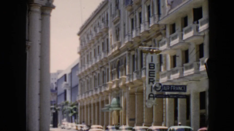 1956 Cuba urban street view with Iberia and Air France signs, ornate facades, a palm, and mid-century cars at curbside.