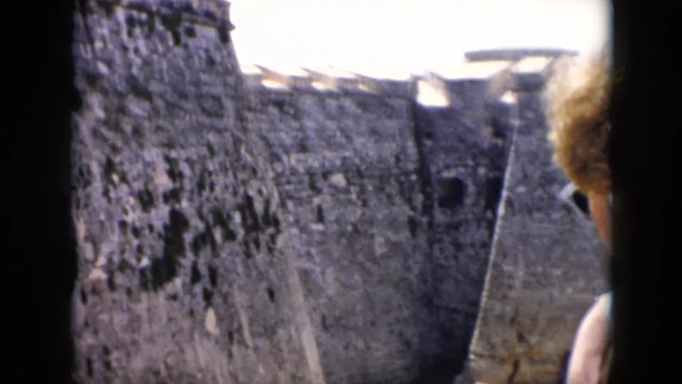 1956 Cuba home-movie view of a rough, mottled fort wall and sloping rampart, with bright sky and washed color typical of 8mm film.