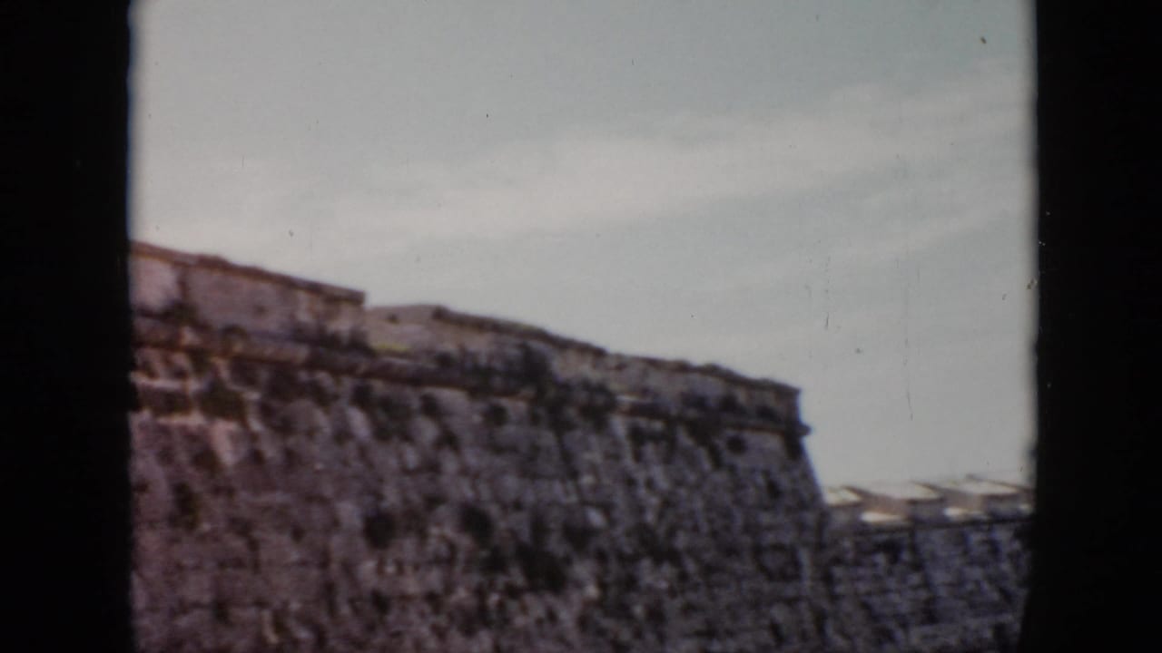 Upper section of a stone fortress wall framed by dark vertical borders and open sky.