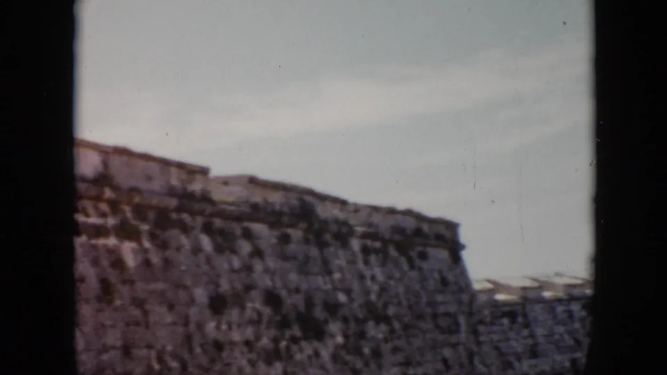 1956 Cuba footage shows the top of an aged fortress wall, with rough masonry and a pale sky beyond the dark frame edges.