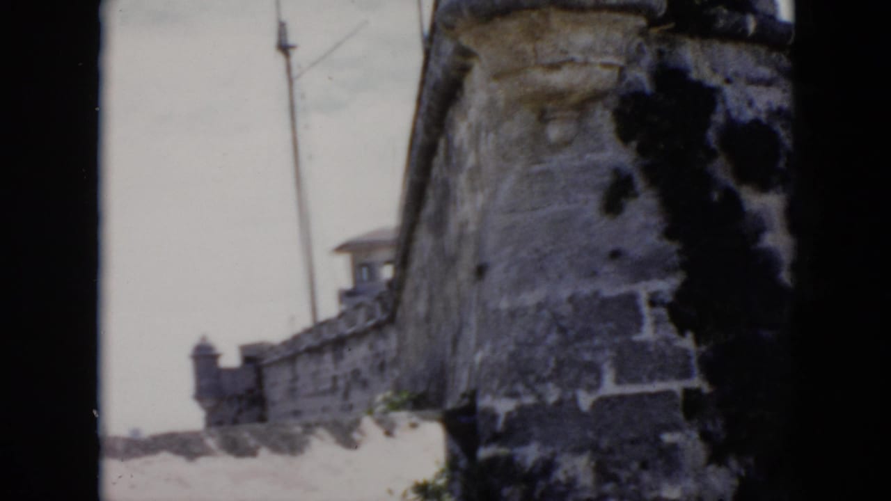 1956 Cuba home-movie frame showing a weathered stone fortress wall near the waterfront.