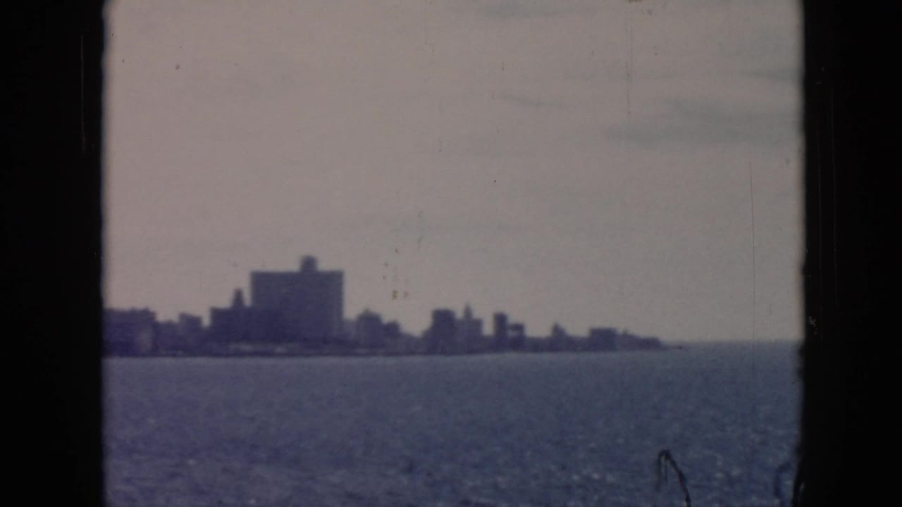 Distant Cuba waterfront seen across the harbor, with soft silhouettes of mid-century buildings and open water.