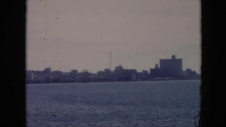 Distant Cuba harbor view with open water, a soft shoreline silhouette, and a prominent dark waterfront building.