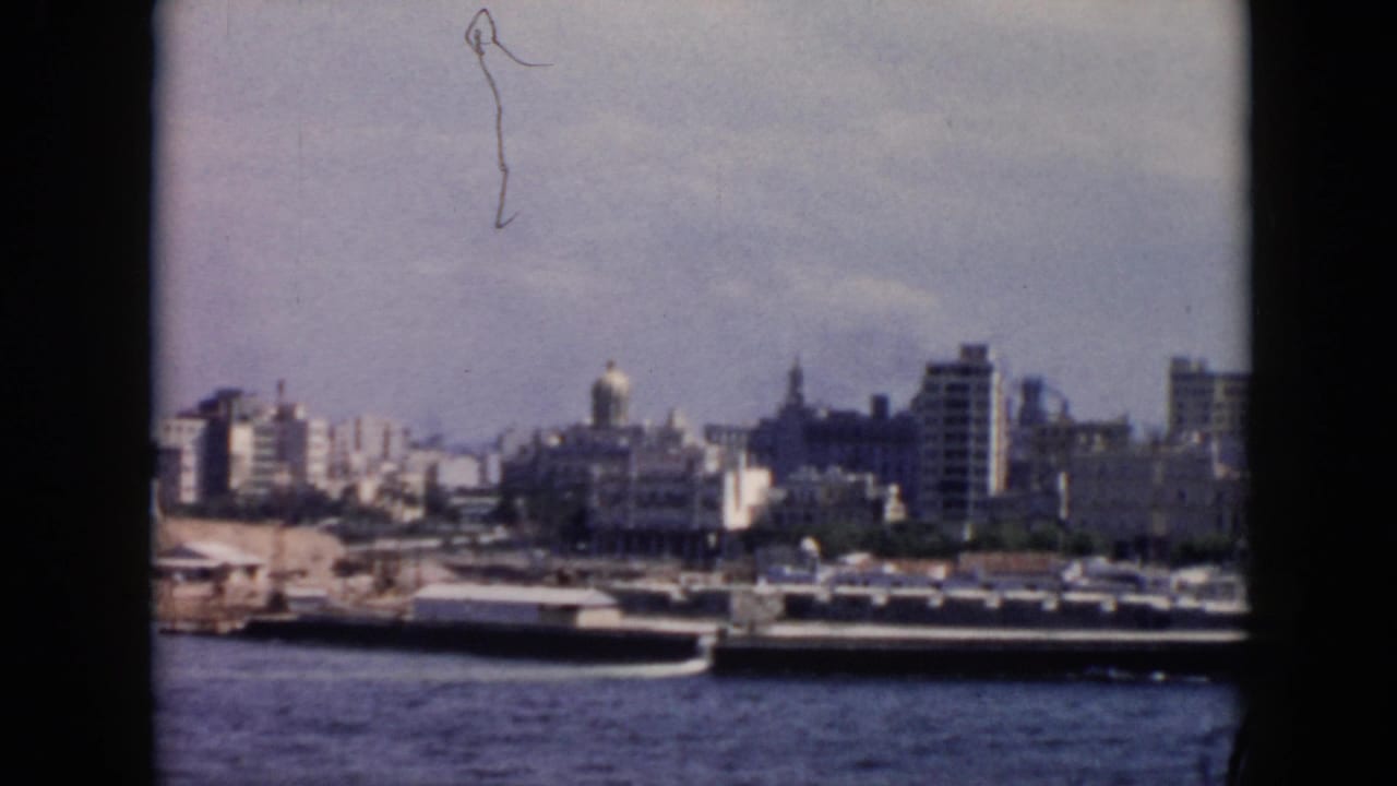 Harbor skyline with boats, quay, high-rises, and a domed structure.