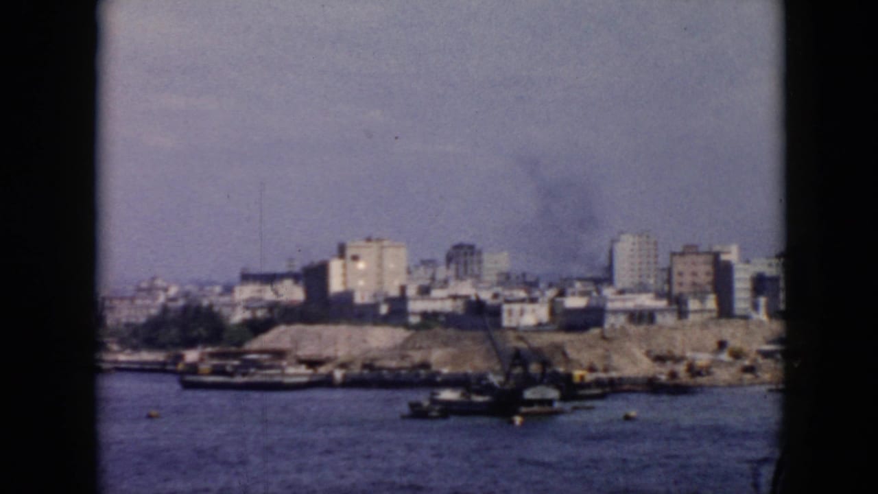 1956 Cuba harbor view from a vessel, with small boats on calm water and low to mid-rise buildings along the shore.