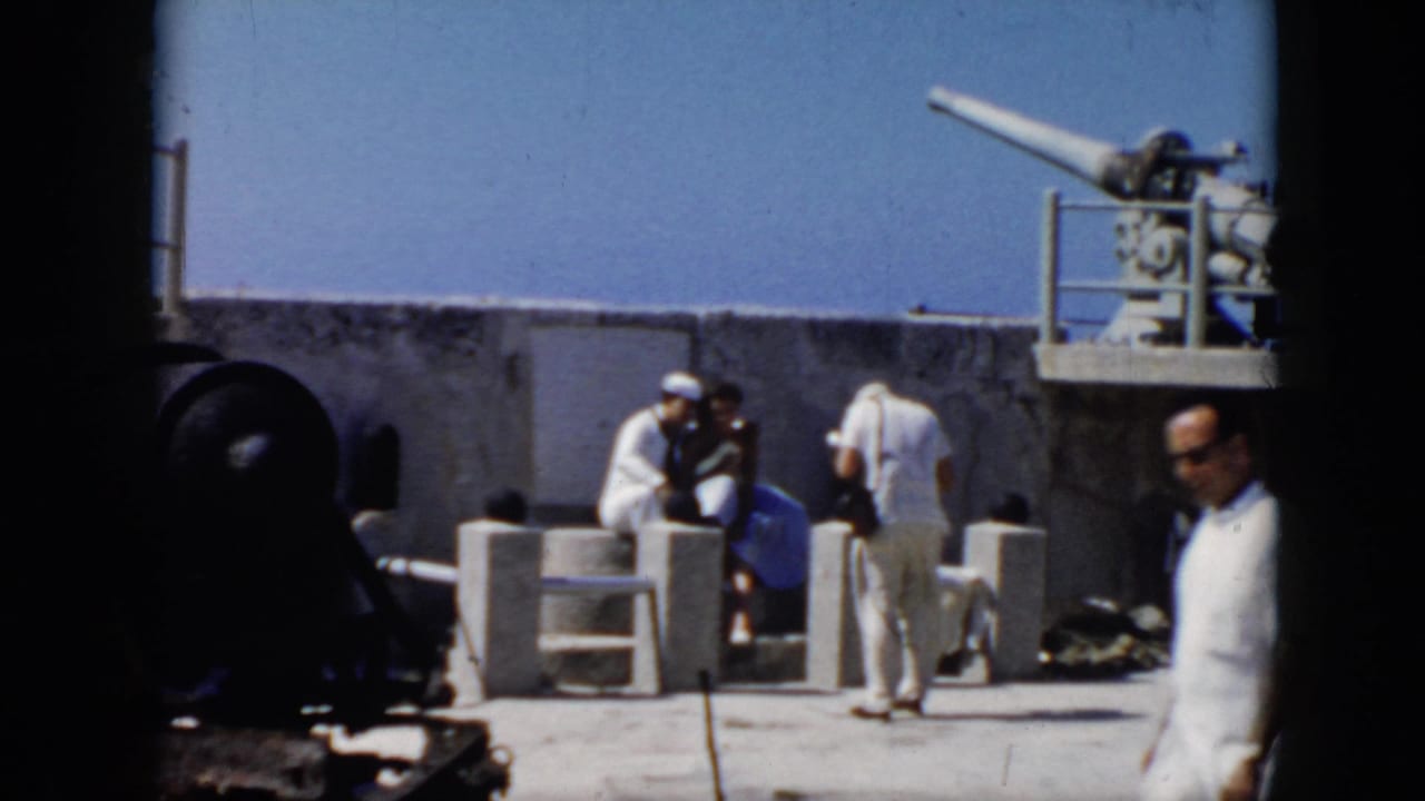 1956 Cuba frame showing U.S. Navy personnel on a concrete coastal platform near a large mounted artillery gun.