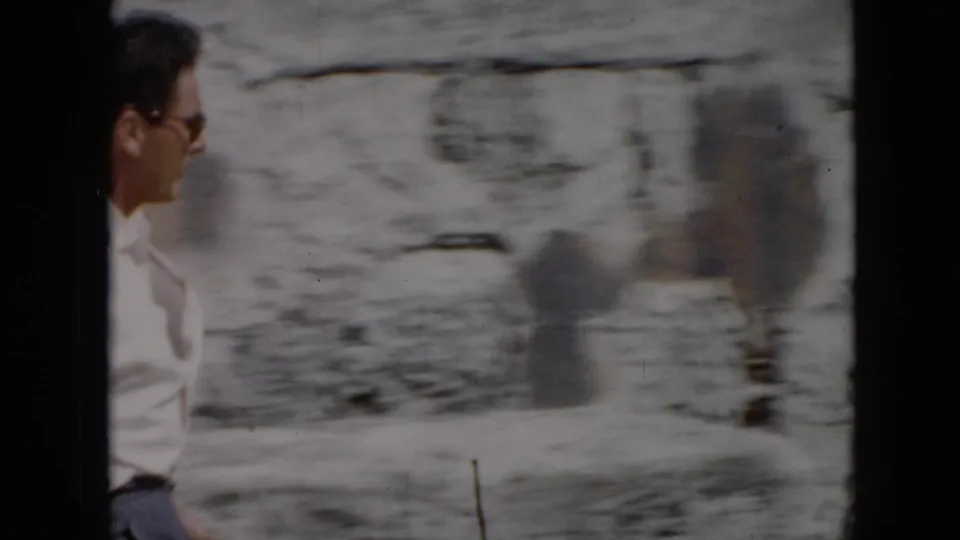 1956 Cuba home-movie frame showing a man in a white shirt near weathered stone walls, partly blurred by handheld movement.