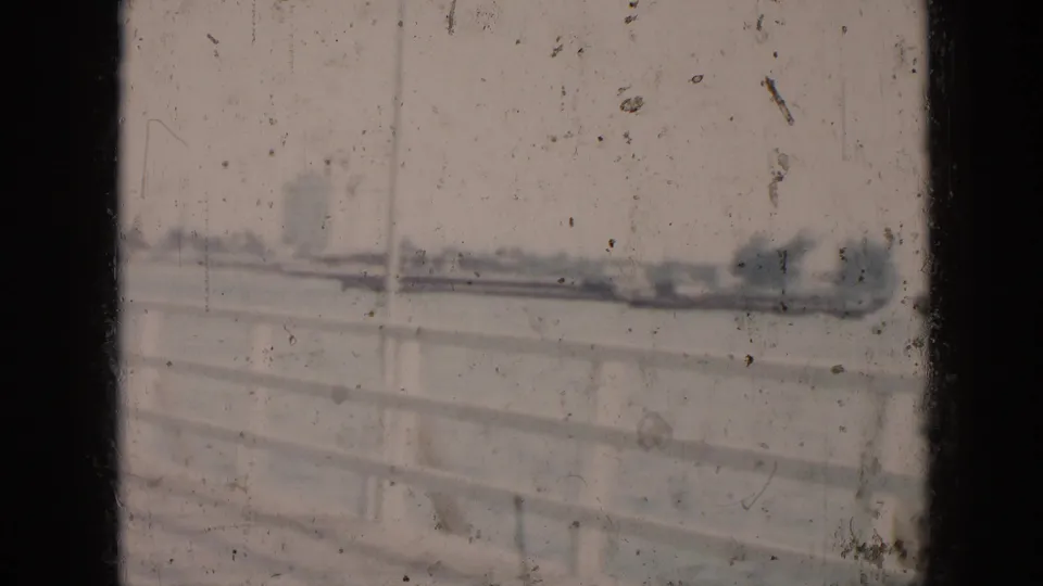 1956 Cuba 8mm frame showing a white railing in the foreground and a soft, distant shoreline across the water.