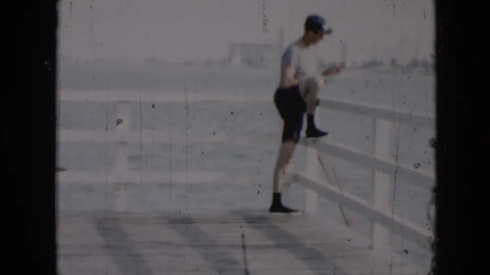 1956 Cuba footage shows a man in casual clothing stretching or leaning on a white waterfront pier railing.