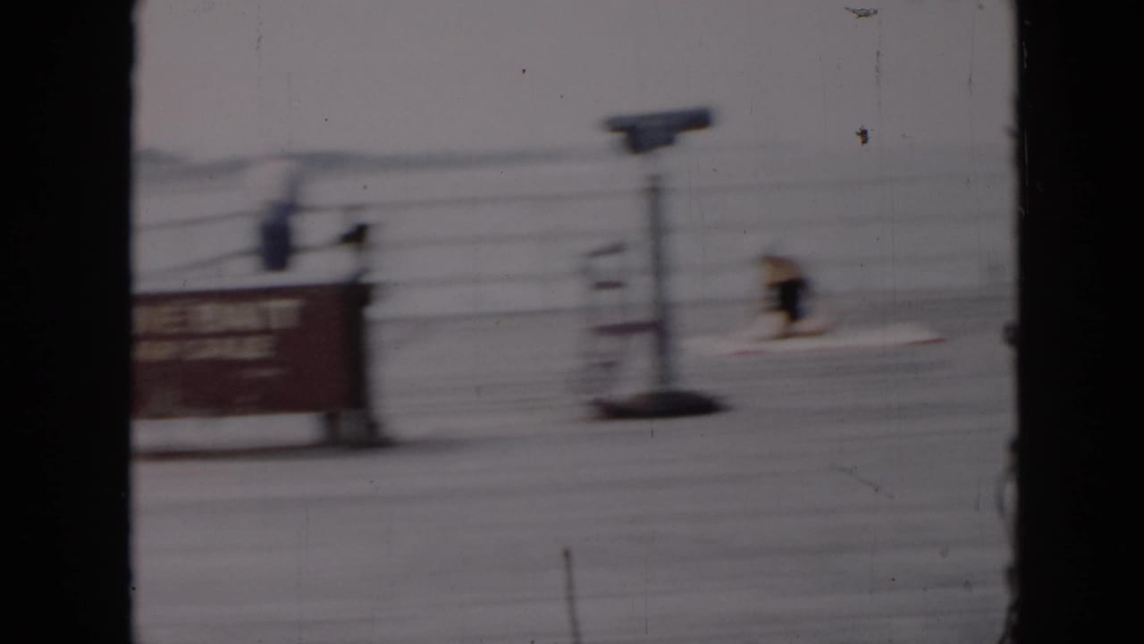 1956 Cuba home-movie frame showing a blurred dockside waterfront view beside a boat, with the woman at the helm partly visible on the right.