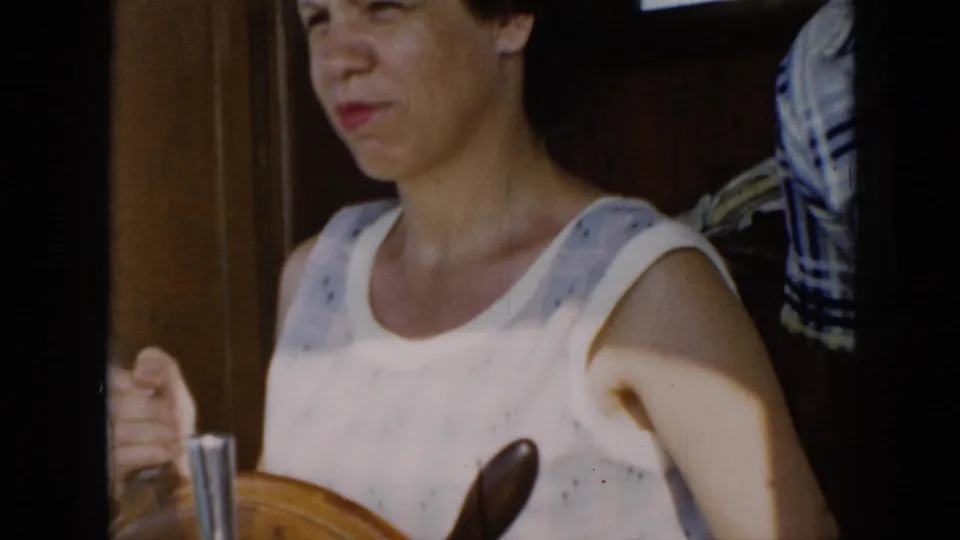 1956 Cuba home-movie close view of the woman gripping the wooden steering wheel inside the boat, with soft focus and grain.