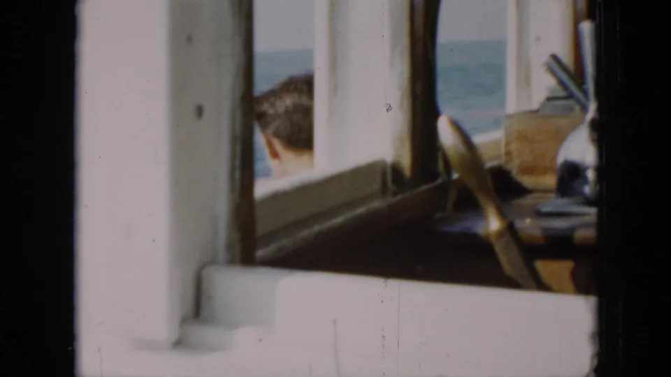 1956 Cuba 8mm bridge detail showing window frames, a wooden wheel, console hardware, and sea outside.