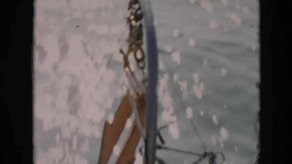 1956 Cuba 8mm detail of boat hardware, possibly anchor or rigging, hanging against sunlit water beside the vessel.