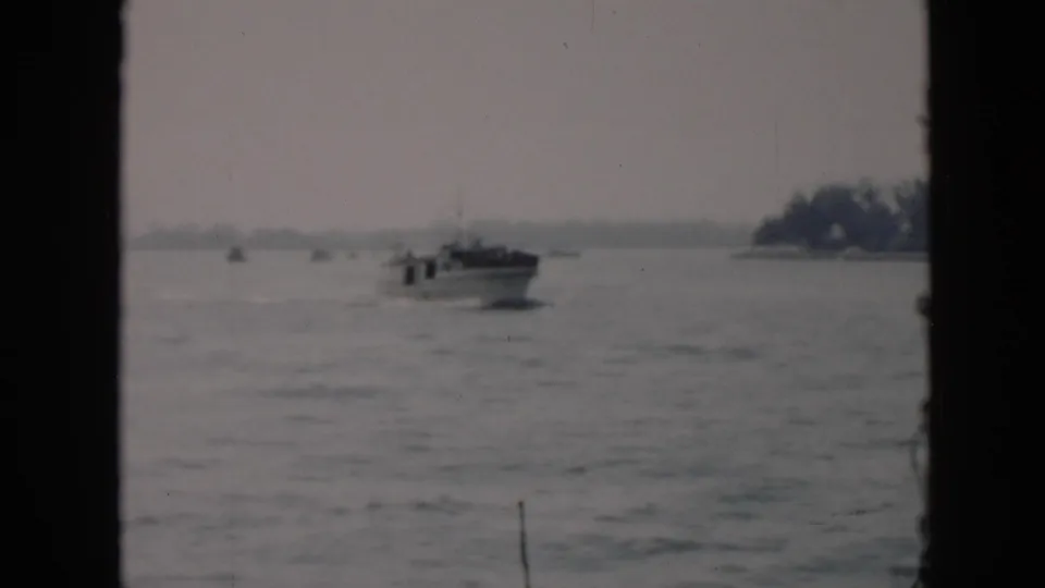 The motorboat continues across choppy Cuban coastal water, framed by dark vertical film or window borders with trees on the horizon.