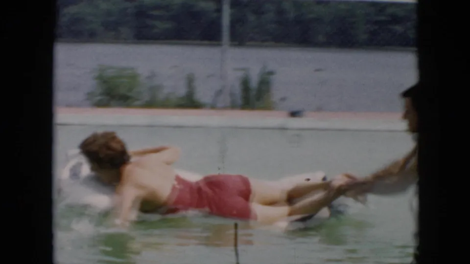 1956 Cuba home-movie frame of the woman splashing on the white float as the playful pool ride reaches its end.