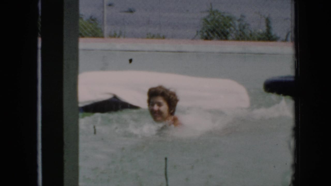 In 1956 Cuba home-movie footage, a woman swims in pale pool water beside a white inflatable raft.