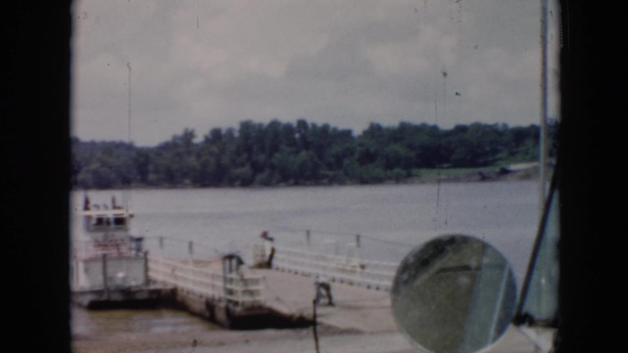 1956 Cuba home-movie view of a ferry dock from inside a vehicle, with a side mirror in front and workers at the pier.