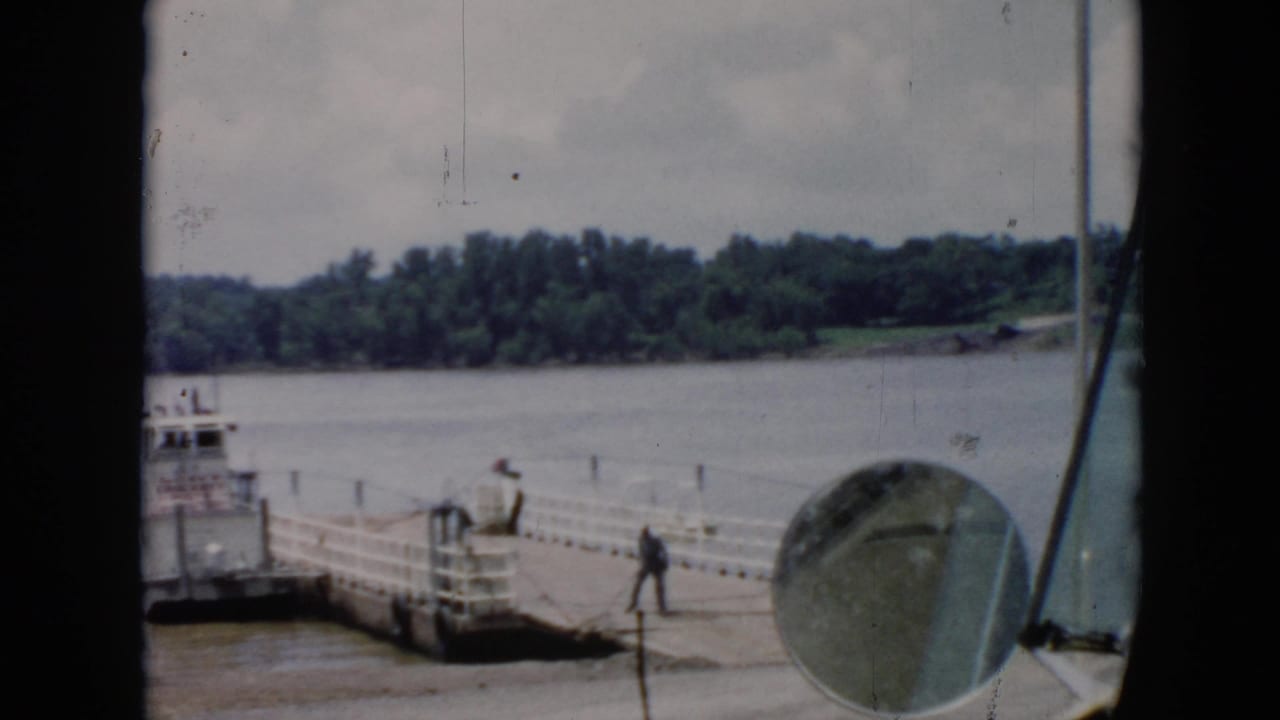 Worker walks along the pier while a ferry sits moored at the left edge of the frame.