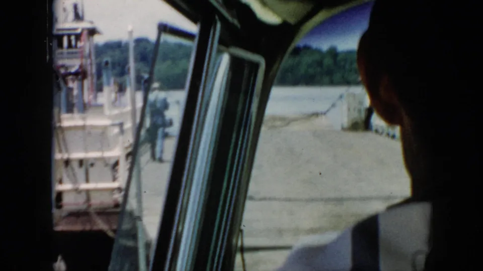 Passenger-view 1956 Cuba footage shows a silhouetted person inside the cabin and a wooden landing beside calm water.