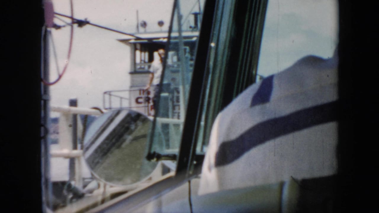 1956 Cuba home-movie view through vehicle windows toward a white ferry with railing, convex mirror, and pilothouse structure.