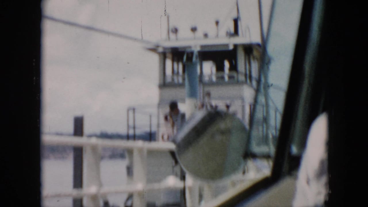 White ferry deck and pilothouse with a person visible near the railing.
