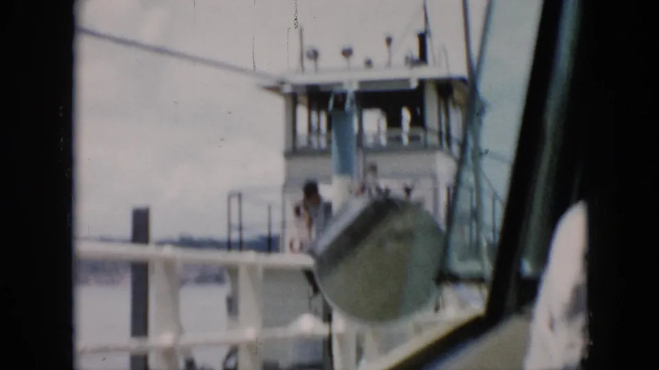 1956 Cuba 8mm frame showing the ferry deck and pilothouse through vehicle glass, with one person in a light shirt on deck.