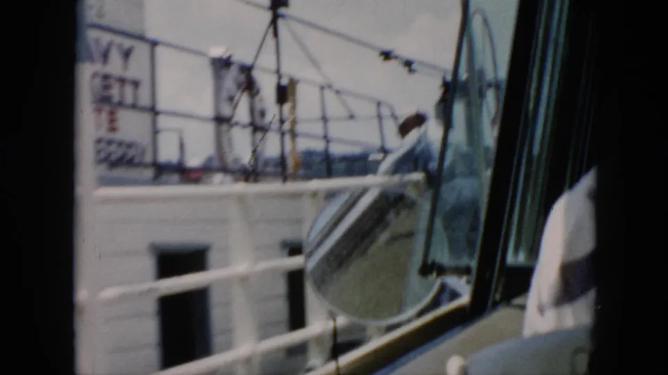 1956 Cuba ferry view through vehicle glass, showing deck railings, a lifeboat-like form, window framing, and partial signage in soft focus.