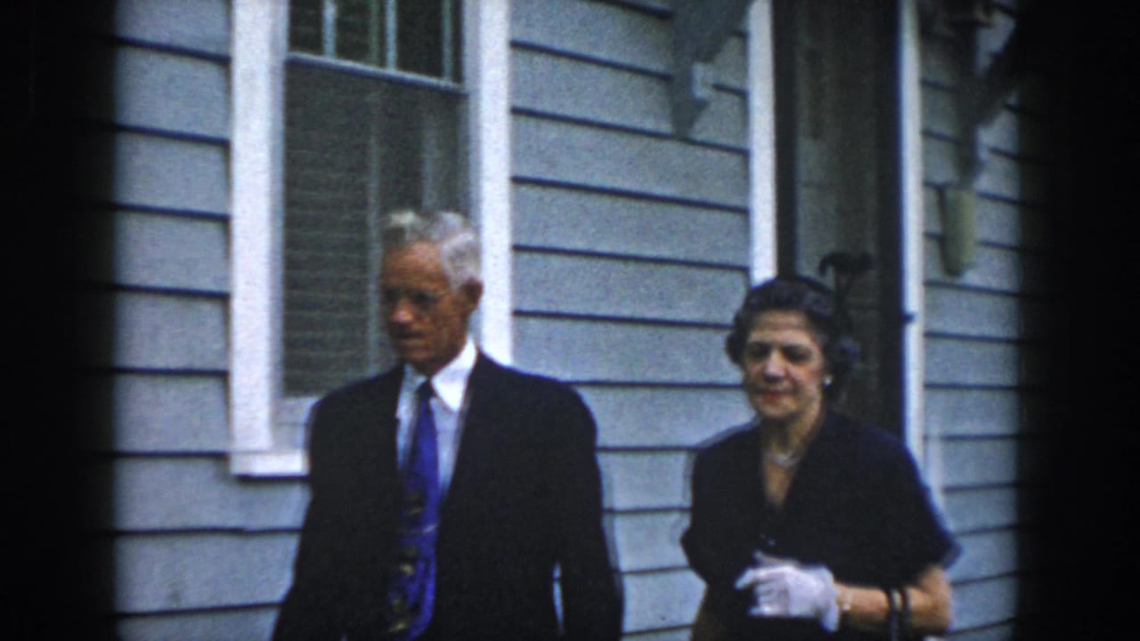 The formally dressed couple continues walking beside the clapboard house in the Dayton, Ohio home-movie scene.
