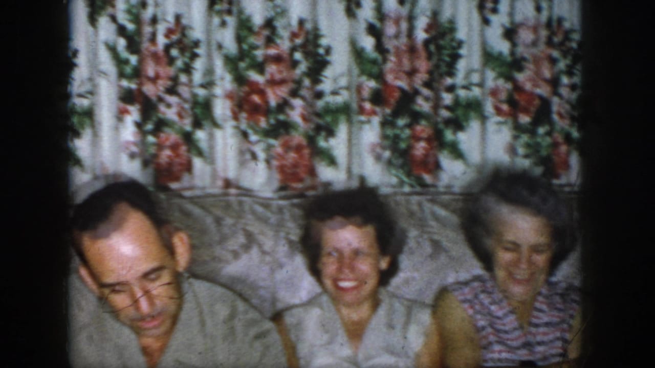 A man and two women seated on a couch, with one woman smiling toward the camera.